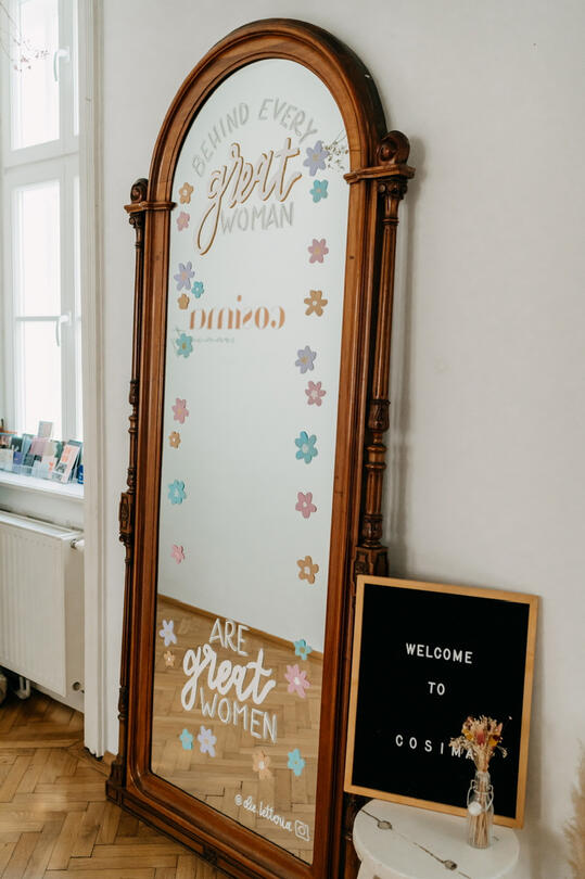 Das Bild zeigt einen mit Blumen und Text bemalten Spiegel.